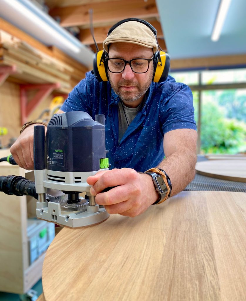 Adam of Eastwood Design sanding table tops in his Northland workshop