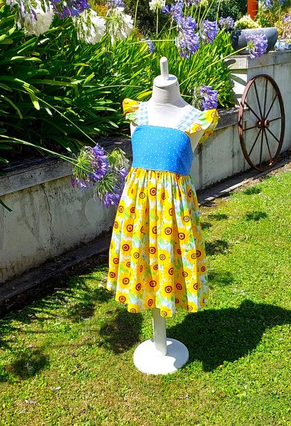 Beautiful bright sunflower dress with flutters.  Ties into a bow over the elasticized back.  Sizes 1 & 7 available